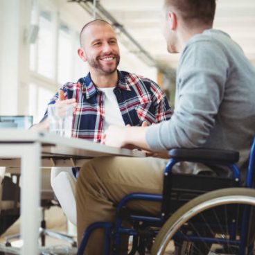 Handicap businessman discussing while sitting with colleague in creative office